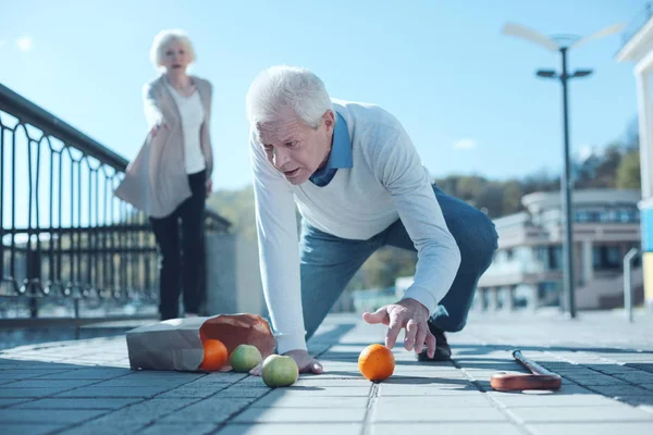 Tired older man falling down with groceries