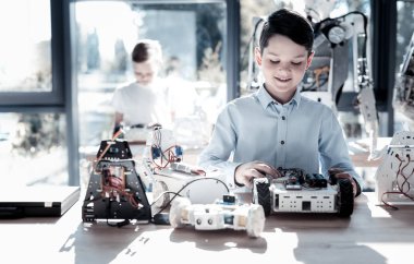 Gülümseyerek şirin okul çocuğu onun kendi kendine hareket eden robot üzerinde çalışma