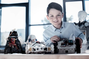 Robot üzerinde çalıştıktan sonra kameraya gülümseyen meraklı küçük çocuk