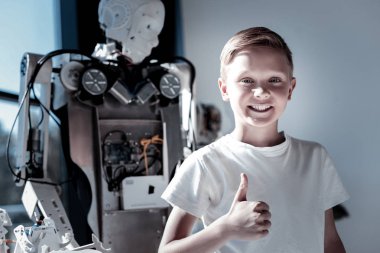 Robot yanında duran ve yukarı thumbing memnun çocuk