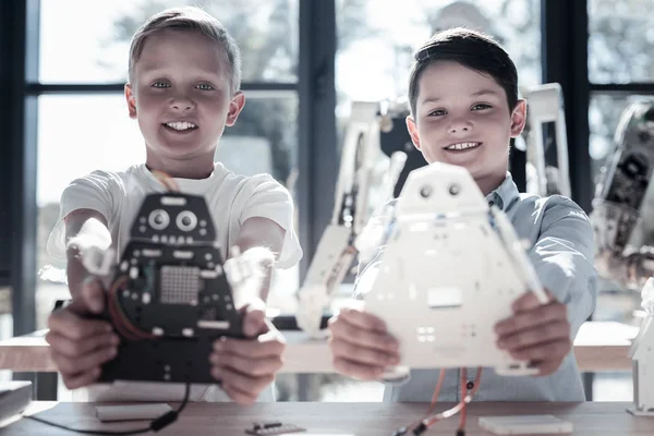 Satisfied preteen boys showing their robotic machines — Stock Photo, Image
