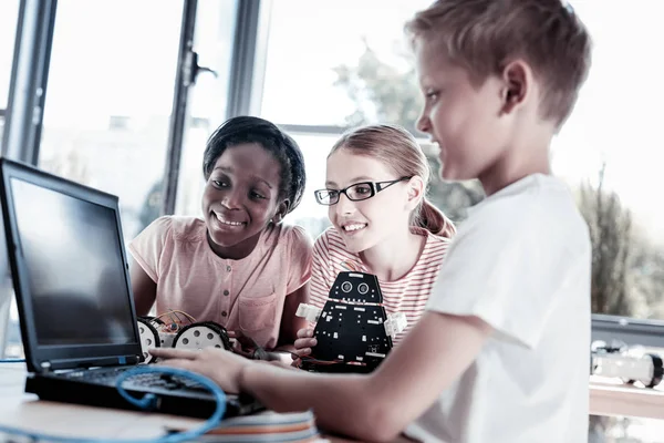 Niños sonrientes diseñando programas para sus máquinas robóticas — Foto de Stock