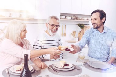 Teşekkür ederiz. Güzel anne givign parçası cheesecake yetişkin oğlu birlikte tablo ve enjoyign yemek otururken memnun