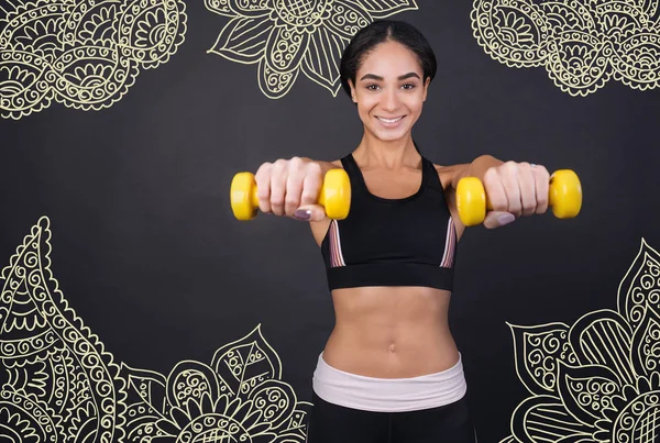 坚强的女人 积极的年轻微笑运动员感到高兴 而在她最喜欢的健身房和训练与小黄手重量 — 图库照片