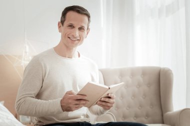 Bir kitap ve gülümseyen memnun akıllı adam.