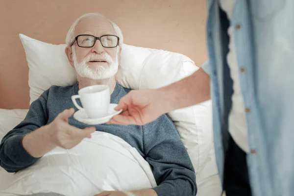 Senior unerschütterlicher Mann liegt und nimmt eine Tasse. — Stockfoto