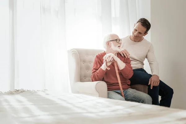 Interesado hombre cariñoso sentado y hablando con su padre . — Foto de Stock