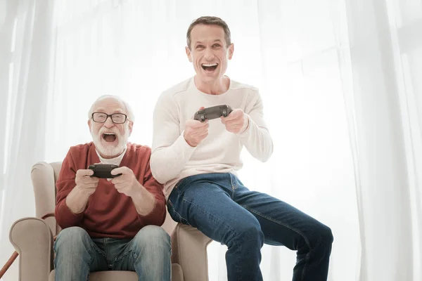 Agradables nativos alegres divirtiéndose juntos y jugando videojuegos . — Foto de Stock