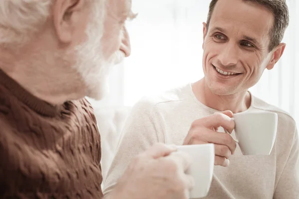 Красивий приємний чоловік посміхається і п'є чай . — стокове фото