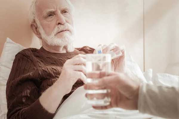 Unglücklich erschöpfter Mann liegt und nimmt Tabletten. — Stockfoto