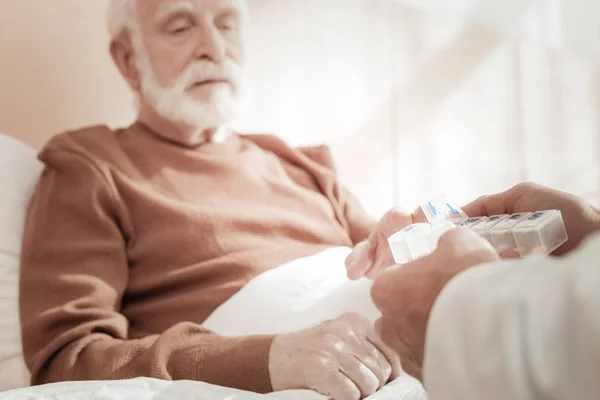 Gamla sjuka mannen sitter och tar piller. — Stockfoto