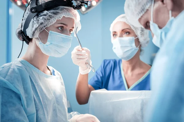 Ładne poważne chirurg ogląda jej koledzy — Zdjęcie stockowe