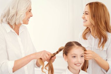 Parlak kadın küçük kız için Ponytails yaparken gülümseyen