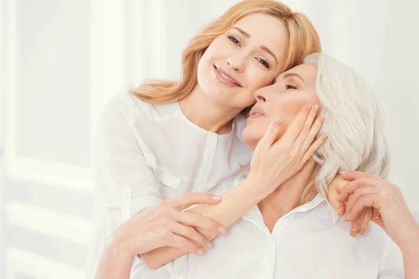 Zarte erwachsene Tochter umarmt ihre Mutter mit Liebe — Stockfoto