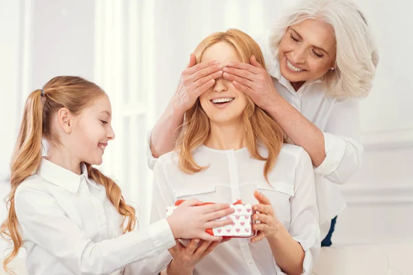 Tender daughter and grandma giving present to amazed mom — Stock Photo, Image