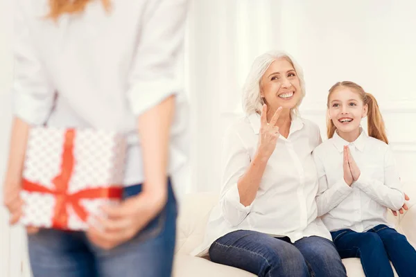 Excited daughter and senior lady waiting for present from mom — Stock Photo, Image