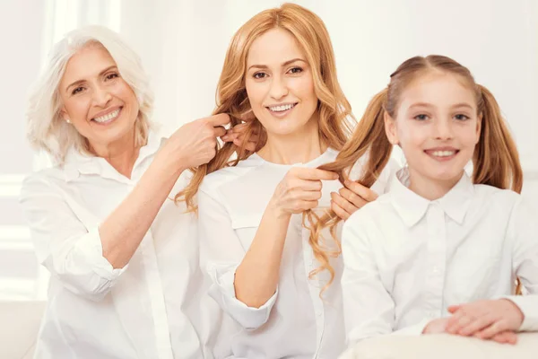 Beaming family female members braiding hair together — Stock Photo, Image