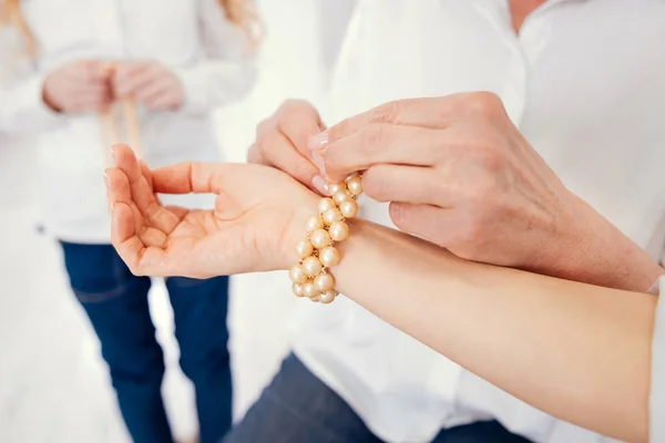 Mindful lady helping daughter to put bracelet on arm — Stock Photo, Image