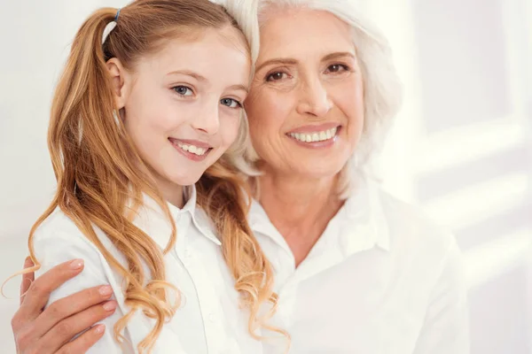 Portret van mooie senior dame omhelst charmante kleindochter — Stockfoto