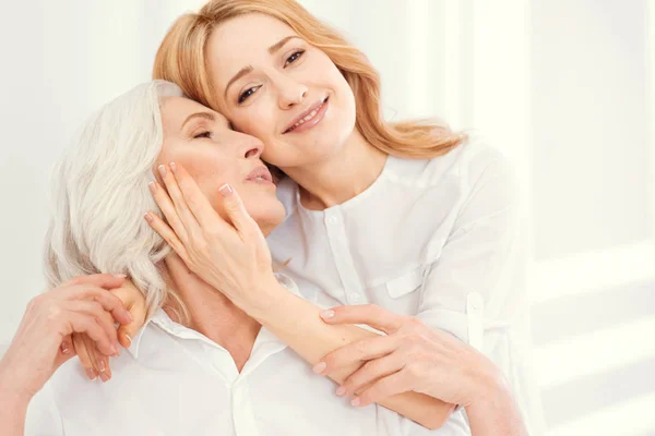 Liefdevolle dochter haar senior moeder thuis te knuffelen — Stockfoto