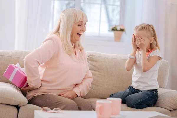 Donna anziana deliziata che nasconde un regalo — Foto Stock