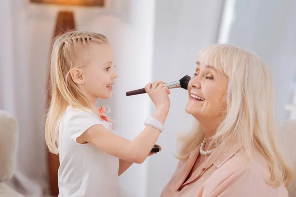 Linda niña haciendo maquillaje para su abuela — Foto de Stock