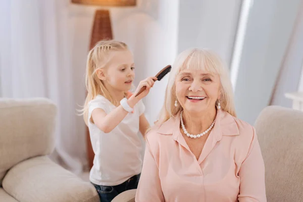 Chica positiva haciendo un peinado para su abuela — Foto de Stock