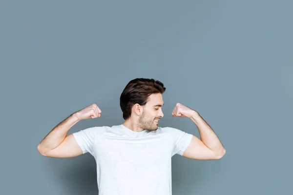 Feliz homem bem construído olhando para seus músculos — Fotografia de Stock