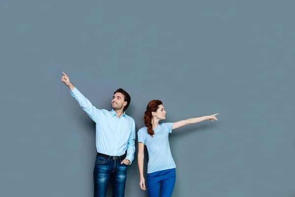 Joyful young people pointing at different sides — Stock Photo, Image