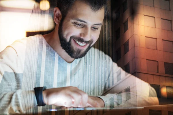 Positiv mannen leende medan du tittar på skärmen på hans lilla tablett — Stockfoto