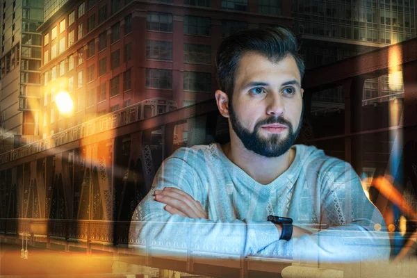 Calm young man sitting alone and thoughtfully looking into the distance