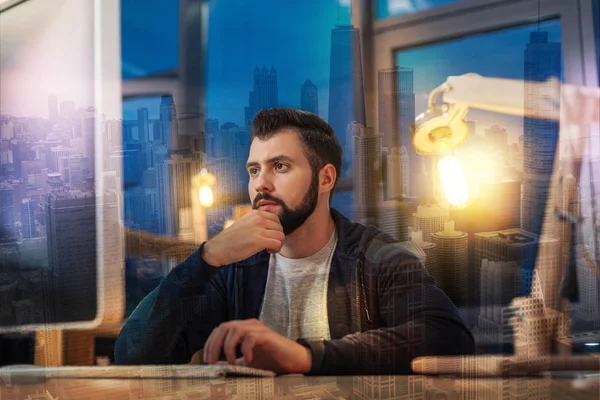 Doordachte specialist kijken naar het scherm van zijn computer tijdens het werken — Stockfoto