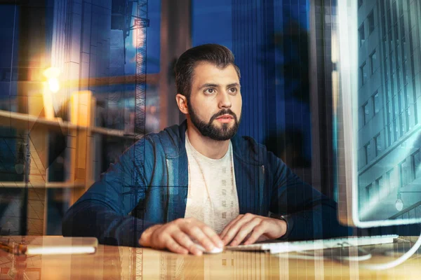 Bearded man looking attentively at the screen while working alone — Stock Photo, Image