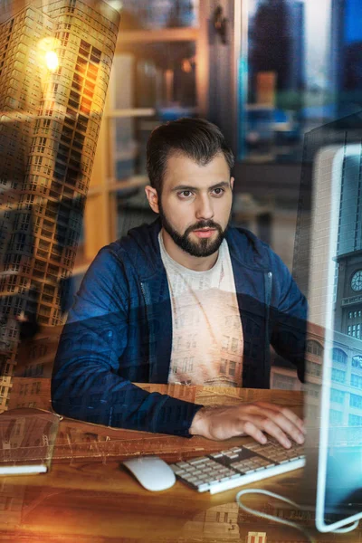 Hombre concentrado mirando el monitor mientras trabaja en su oficina — Foto de Stock