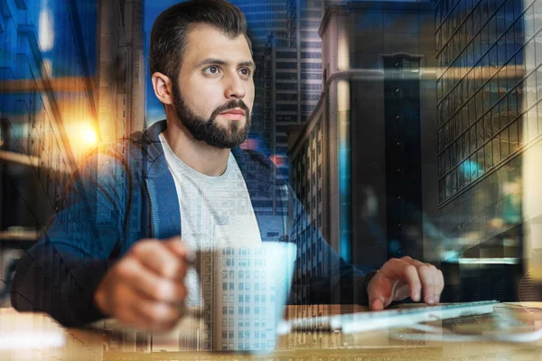 Concentrated man working in his office while drinking tea — Stock Photo, Image