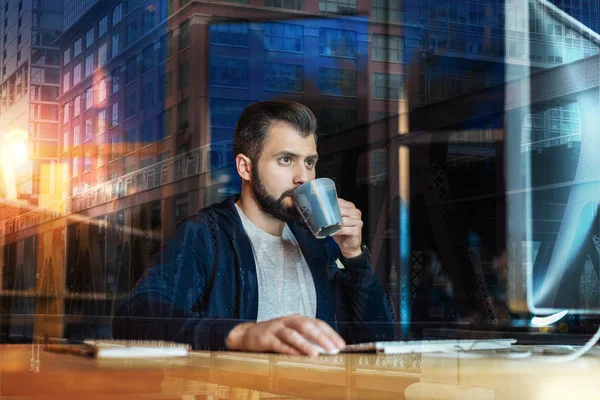 Lugn specialist dricka te och titta på skärmen på hans dator — Stockfoto