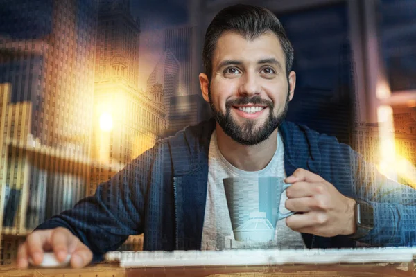 Glada skäggig man ler medan dricka te på jobbet — Stockfoto