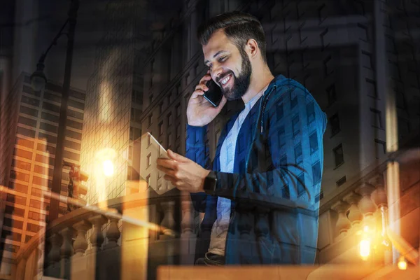 Positiv man pratar i telefon och tittar på hans gadget — Stockfoto