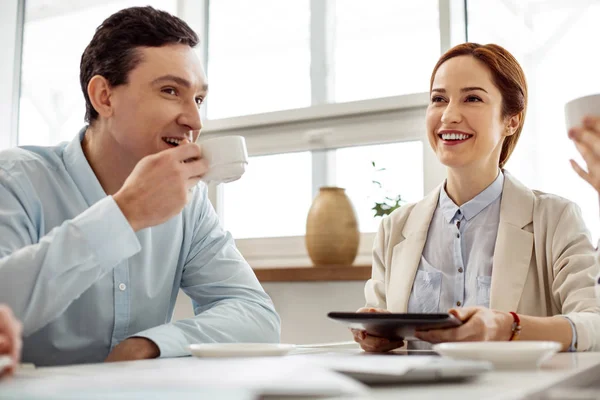 Smiling woman holding a tablet and sitting with her friend — Stock Photo, Image