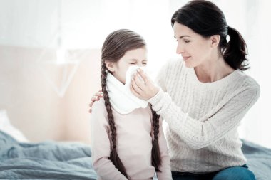 Oturma ve bir peçete tutan bakım özenli anne.