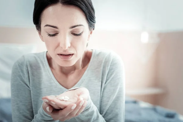 Unhappy disappointed woman sitting and holding pills. — Stock Photo, Image