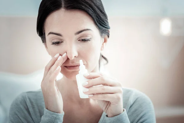 Mujer enferma pensativa mirando hacia abajo y sosteniendo un spray nasal . — Foto de Stock