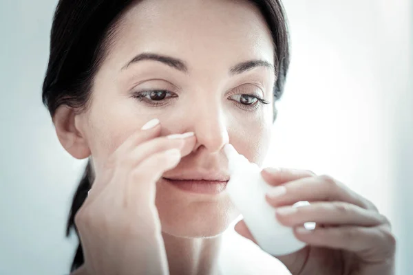 Pleasant satisfied woman smiling and using nose spray. — Stock Photo, Image