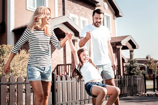 Vrolijke aangename ouders houden dochters handen spelen met haar. — Stockfoto