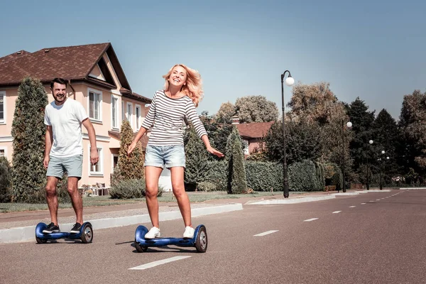 Feliz joven pareja divirtiéndose montando en los scooters auto-equilibrados . — Foto de Stock