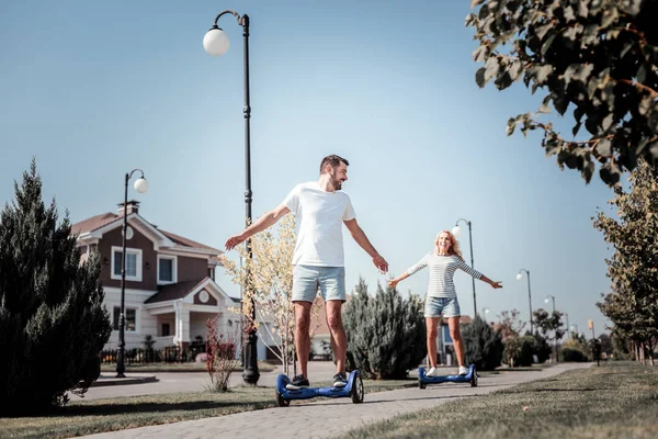 Радостная заинтересованная пара весело катается на самобалансирующемся скутере . — стоковое фото