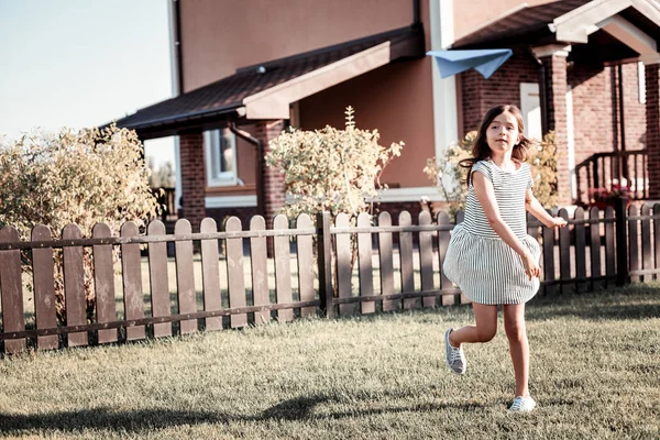 Concentrated cute girl running and throwing a paper plane. — Stock Photo, Image
