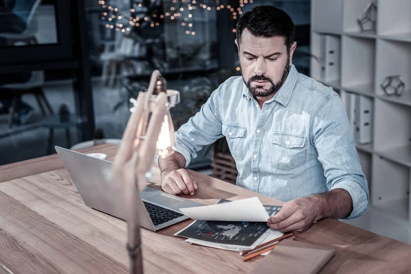 Ocupado hombre serio sentado y pasando por alto los papeles . — Foto de Stock