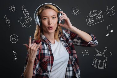 Kulaklıklar giyen ve bir keçi jest yapmak genç kadın