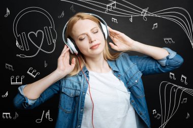 Sakin genç kadın kulaklık müzik dinlerken gözlerini kapatma